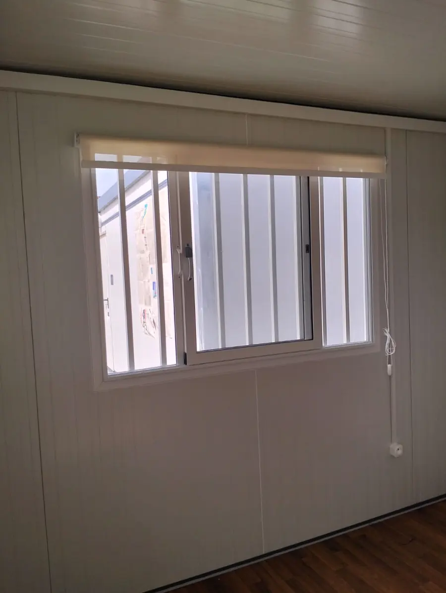 Fenêtre coulissante en aluminium avec store enrouleur dans un module préfabriqué aux murs en panneaux blancs