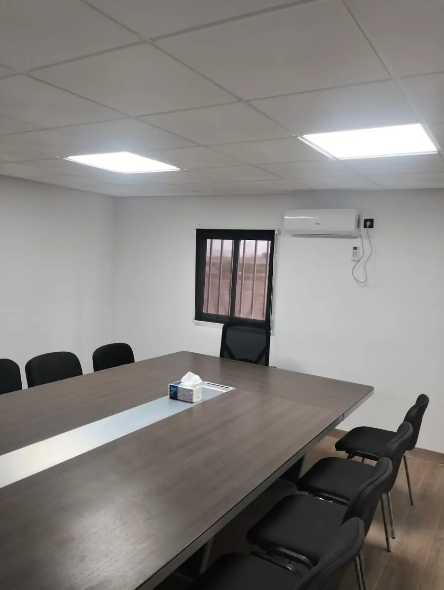 Salle de réunion aménagée avec faux plafond, éclairage LED, climatisation et grande table