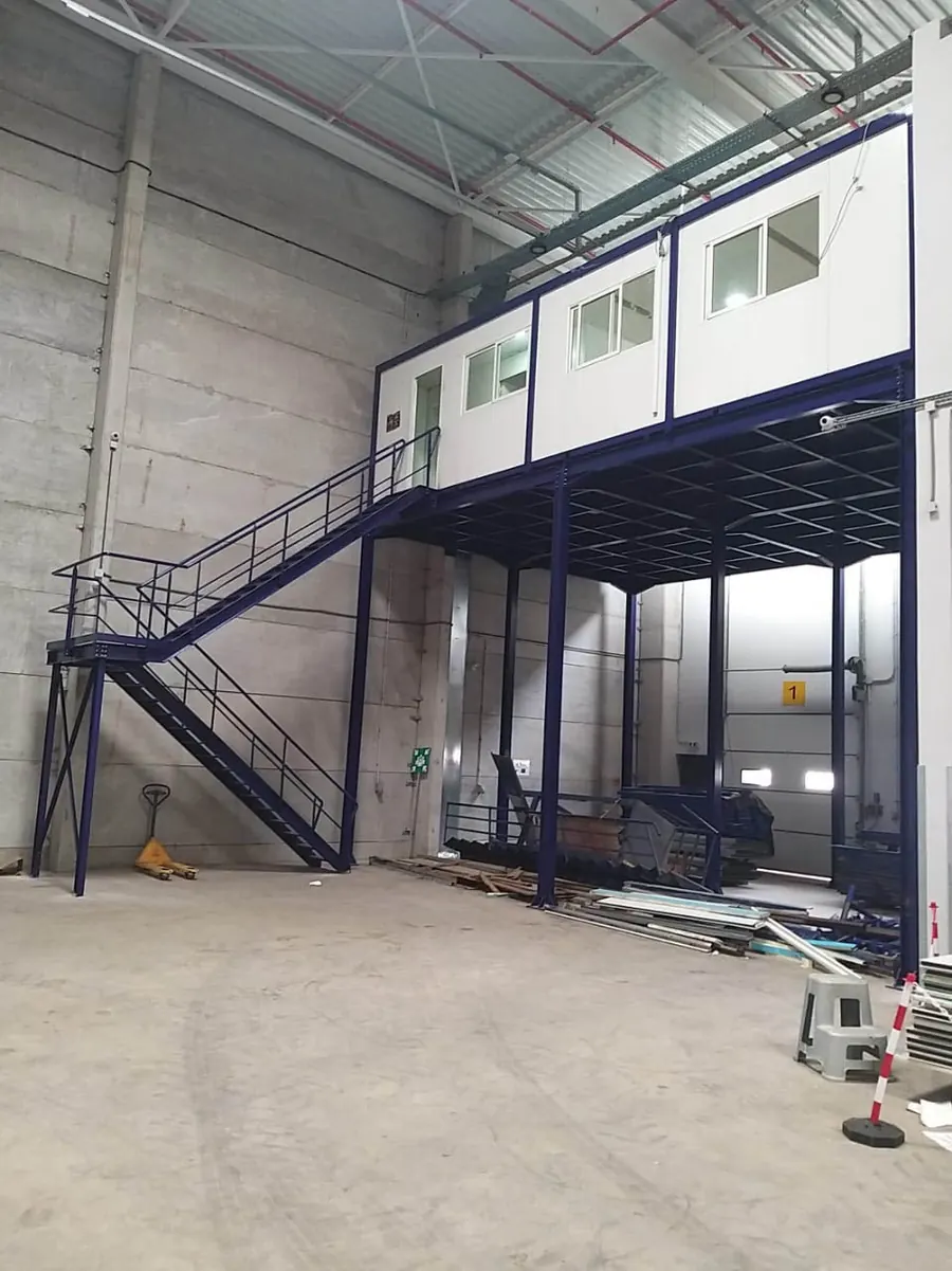 Mezzanine métallique avec escalier et bureaux modulaires à l'étage, réalisée par SLOTIM dans un entrepôt