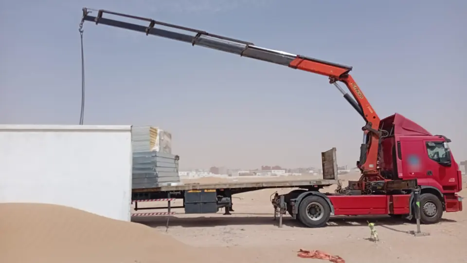 Camion-grue avec bras de levage déployé, prêt pour une opération de grutage sur chantier